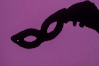 silhouette of a hand holding a mask