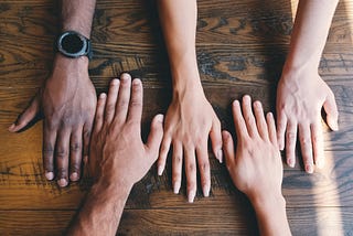 Image shows four different. hands with different skin colours — representing differences in nationalities and cultures