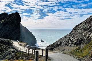 A hiking path between two cliffs looking out to the Pacific Ocean