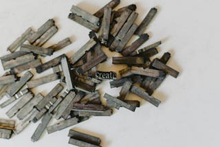 A scatter of pieces of metal moveable type, in the center a slug which can be read to bear the word “create”