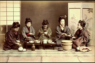 Five pre-modern Japanese women in kimono and old-fashion hairstyles eating lunch together.