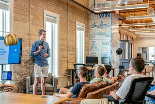 Man giving speech to room of workers in a studio.