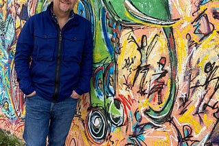 The author stood in front of a wall covered in graffiti