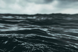 A closeup of the water in a stormy sea, clouds threatening in the distance