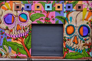 A brightly painted wall with two skulls.
