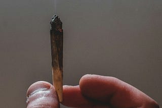A hand holding a lit joint.