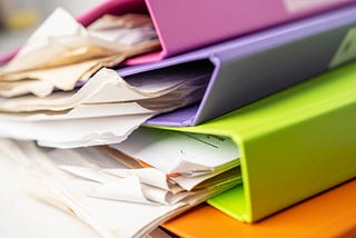 Stack of messy binders with paper coming out.