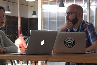 Woman and man in conversation at an office with their laptops open