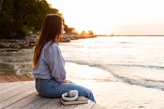 A woman looking at the sea at sunset.