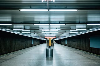 An empty underground station is eerily lit, blues and greys giving a somber mood.