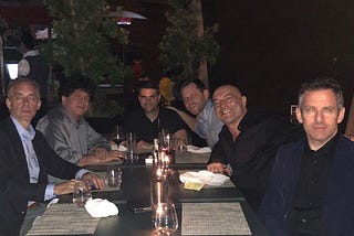 Jordan Peterson, Eric Weinstein, Ben Shapiro, Dave Rubin, Joe Rogan, and Sam Harris sitting at a table together in a dining or drinking establishment.