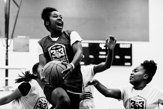Girl basketball player going in for the dunk with an expression of joy and delight