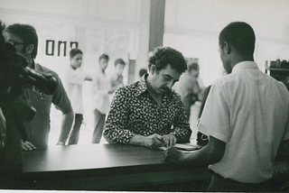 Marquez signing a book at a book signing event. Black and white photo.
