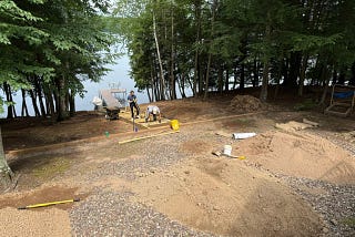 Hillside to a lake with a dock having a walkway built, surrounded by stone.