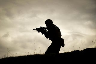 A man in a black jacket holding a rifle.
