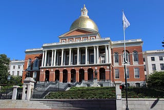 Front of the Massachusetts State House on a sunny day.