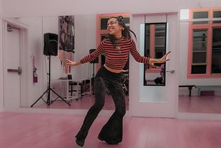 A young woman, the author, dances in a colorful dance studio — she looks happy.