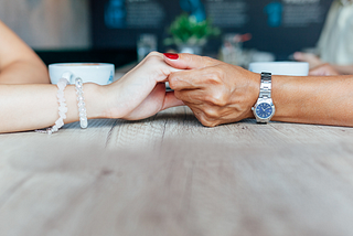 Two women holding hands supportively.