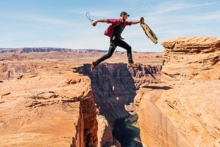 A man jumps over a fault in a canyon