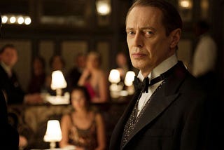 Man in 1920s tuxedo standing in dimly lit speakeasy nightclub