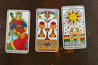 Three tarot cards: Queen of Wands, Two of Cups, and The Sun.