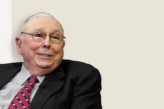 Charlie Munger, dressed in a black suit, striped shirt, and a red / blue striped tie