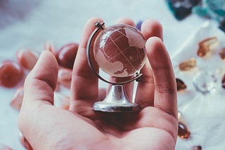 person holding globe paperweight in their hand