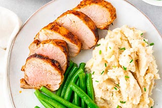 sliced air-fried pork tenderloin served with mashed potatoes and green beans