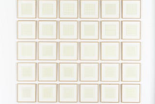 A grid arrangement of framed prints of grids on bright white paper.