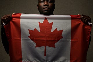 Black man with a concerned face holding Canadian flag