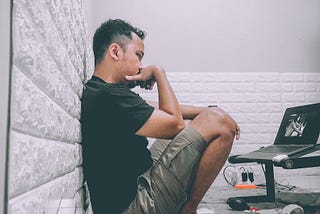 A man sits in front of his laptop looking frustrated and uncertain.