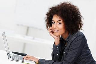 Woman with natural hair typing on laptop