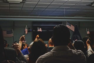 A crowd of people waving small American flags