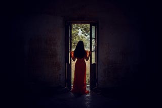 A woman stands in front of a window to show someone standing by the door to help others