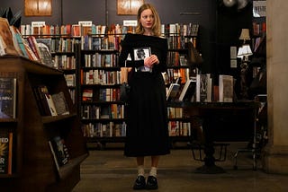 A woman standing in a bookstore holding a book