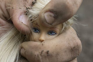Barbie doll in man’s fist, showing oppression of women