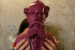 A bust of Charles Dickens is held aloft.