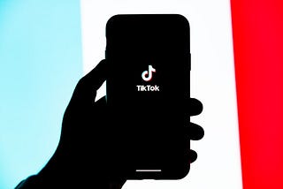 Hand holding cell phone with TikTok logo showing