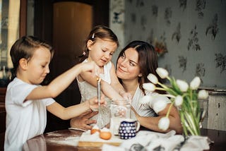 Mom with 2 kids cooking in the kitchen.