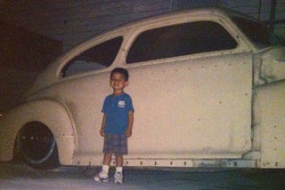 Small child standing in front of a classic car from the early 1940's