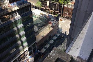 A view from the apartment down to the city street, with a construction site next door