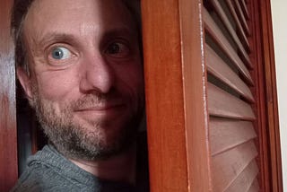 Tucker Lieberman, coming out of the closet, half in shadow, looking surprisey and sneaky
