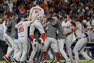 a crowd of red sox players gather in a pile celebrating their win