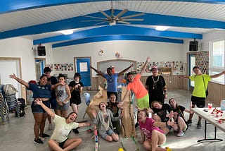 campers and staff gather arounnd their construction of a marbel tunnel and hold their arms out wide while they look excited for the camera