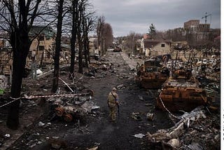 A Ukrainian soldier walks amongst destroyed town and Russian tanks.