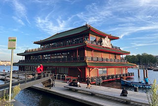 this is a photo of a chinese restaurant that looks like a large boat floating on the water. It has a sign saying Sea Palace on the side