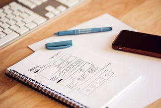 Photo of a notebook with a drawing of a wireframe.