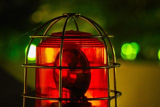 Image shows a red emergency light in a gold-colored wire cage on top of an emergency vehicle.