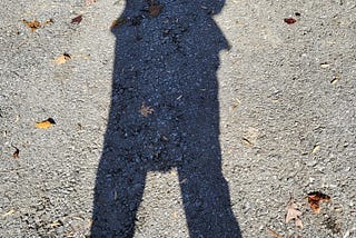 The author’s shadow as she stands still on the driveway pavement.