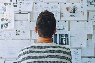 Man looking at wall of paper | Photo by Startup Stock Photos from Pexels